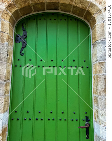 Green door with black iron hardware, arched top in style of stone architecture Green door with black iron hardware, arched top in style of stone architecture 130157410