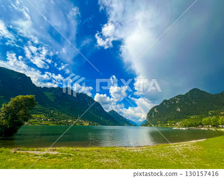Serene Lake Idro Surrounded by Majestic Mountains and Cloudy sky, Italy, Crone Serene Lake Idro Surrounded by Majestic Mountains and Cloudy sky, Italy, Crone 130157416