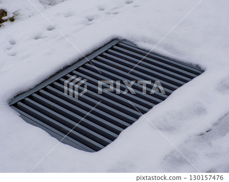 A sewer grate that is not fully cleared of snow and ice. A sewer grate that is not fully cleared of snow and ice. 130157476
