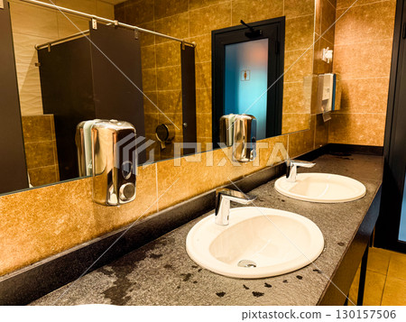 Double sink counter with mirror and soap dispenser in restroom. Cleanliness, hygiene, and facility interior arrangement for hospitality, comfort, and visitor service. 130157506