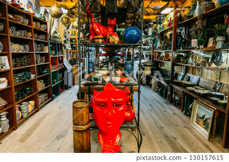 Eclectic shelves filled with ceramic bowls, pottery, and bold decorative objects in a flea market setting. Secondhand culture, flea market economy, decorative reuse, local style loops 130157615