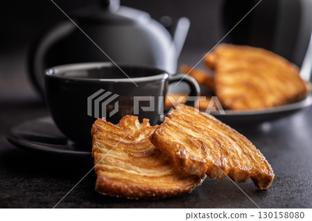 Le sfoglie. Crispy sweet pastry on black table. 130158080