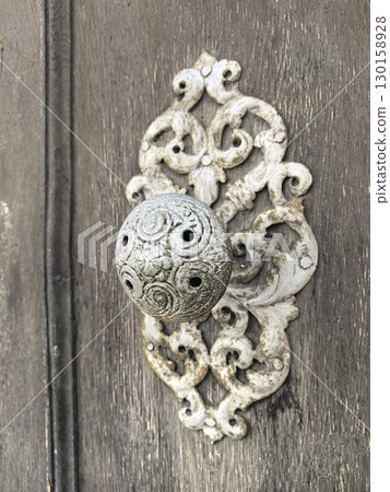 Intricate decorative door handle adds charm to rustic wooden entrance Intricate decorative door handle adds charm to rustic wooden entrance 130158928