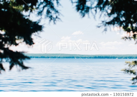 Serene lake view surrounded by trees under a clear blue sky in summer Serene lake view surrounded by trees under a clear blue sky in summer 130158972
