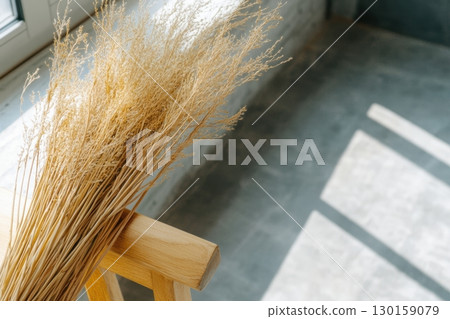 Dried floral arrangement on wooden chair near window in bright interior setting Dried floral arrangement on wooden chair near window in bright interior setting 130159079