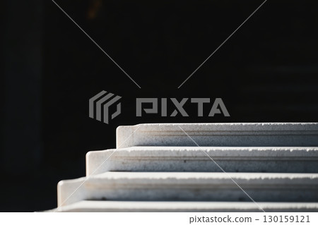 Close-up view of stone steps leading to a dark space in bright sunlight during the day 130159121