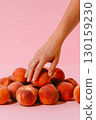 Hand picking peach from pile of ripe fruits on pink background. Healthy eating, summer fruit harvest, organic nutrition. 130159230