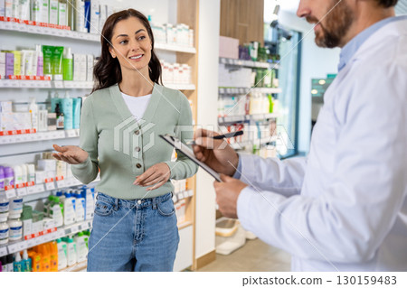 Male pharmacist talking to a woman and making notes 130159483