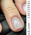 Close-up of glitter gel nail polish on natural short nail in beauty salon. Extreme macro photo of a clean natural short nail 130159581