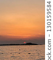Sunrise over the sea with small island silhouette, golden sky and sun reflection on water, tranquil seascape at dawn 130159584