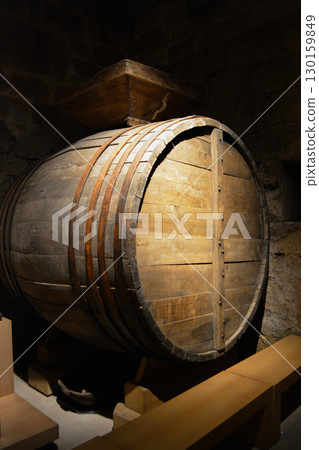 A historic wine cellar with an antique wooden press, grape crusher, and giant barrel. The concept is traditional winemaking heritage and craftsmanship. 130159849