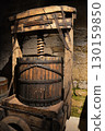 A historic wine cellar with an antique wooden press, grape crusher, and giant barrel. The concept is traditional winemaking heritage and craftsmanship. 130159850