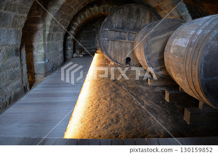 A historic wine cellar with an antique wooden press, grape crusher, and giant barrel. The concept is traditional winemaking heritage and craftsmanship. 130159852