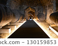 A historic wine cellar with an antique wooden press, grape crusher, and giant barrel. The concept is traditional winemaking heritage and craftsmanship. 130159853