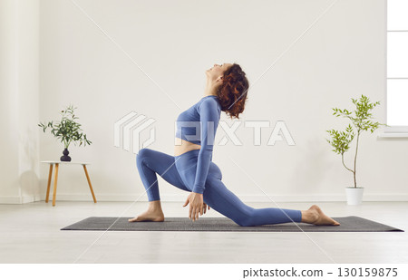 Young sporty woman practicing yoga, doing Horse rider exercise, anjaneyasana pose, working out  130159875