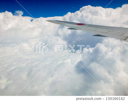A spectacular view of blue skies and a sea of clouds from an airplane window 130160182
