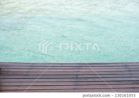 Wooden deck overlooking calm turquoise water for relaxation and leisure Wooden deck overlooking calm turquoise water for relaxation and leisure 130161055