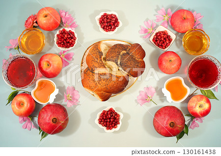 Jewish holiday Rosh Hashanah concept with apples, honey, pomegranate, flowers, red wine and Challah bread for greeting card, creative mockup and template for Jewish New Year. Jewish holiday Rosh Hashanah concept with apples, honey, pomegranate, flowers, red wine and Challah bread for greeting card, creative mockup and template for Jewish New Year. 130161438