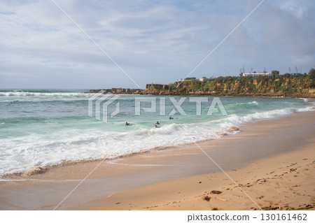 Surfers floating on ocean waves on calm beach 130161462