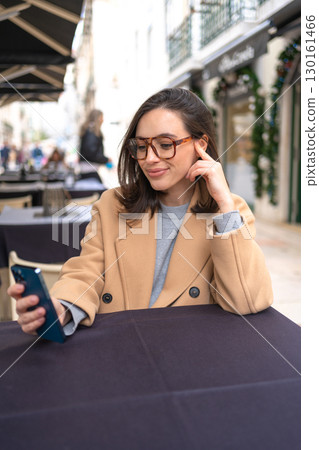 Middle-aged woman using smartphone sitting outdoor 130161466