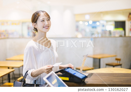A woman making a cashless payment at a cafe register 130162027