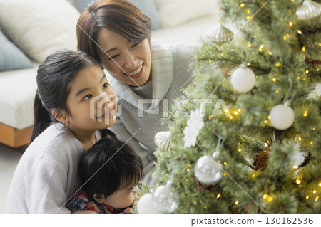 Families decorating Christmas trees 130162536