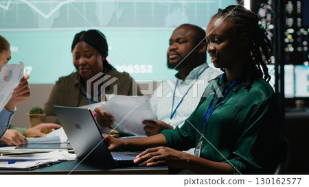Diverse administrative team attending briefing conference at night to verify updates on regulatory changes or industry standards. Business professionals reviewing all data analysis. Camera B. Diverse administrative team attending briefing conference at night to verify updates on regulatory changes or industry standards. Business professionals reviewing all data analysis. Camera B. 130162577