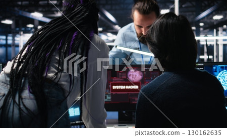 Technicians in AI server hub panicked by hacking attempt stealing sensitive company data. Team of data center IT experts fighting computer virus triggered by security systems, camera A 130162635