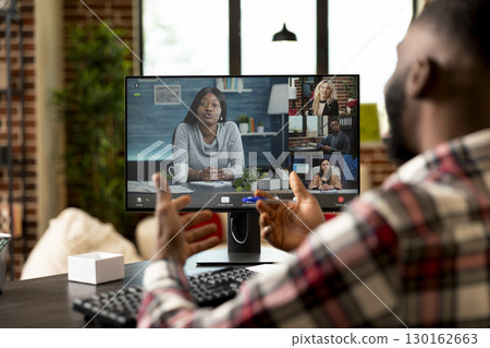 Black male entrepreneur presenting startup project during virtual meeting from home. Sitting at desk with computer, self employed man pitching business ideas to multiethnic investors. 130162663