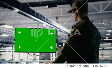 Military data center professional using software on green screen mockup PC to detect enemy threats. Army man in data center uses chroma key computer to detect issues , camera B 130162680