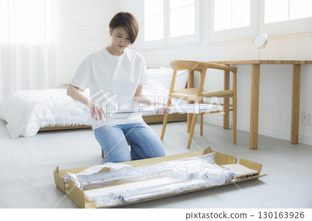 A woman assembling a clothes rack 130163926
