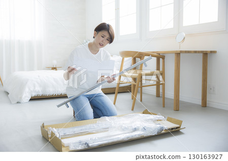 A woman assembling a clothes rack 130163927