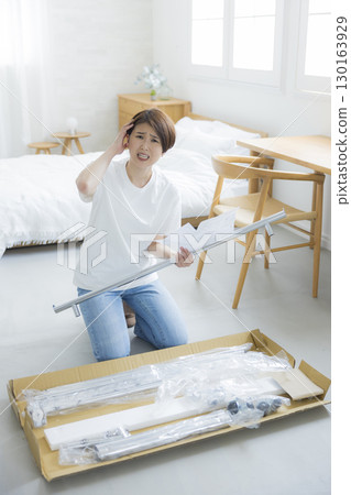 A woman assembling a clothes rack A woman assembling a clothes rack 130163929