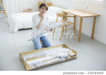 A woman assembling a clothes rack A woman assembling a clothes rack 130163930