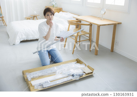 A woman assembling a clothes rack A woman assembling a clothes rack 130163931