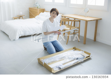 A woman assembling a clothes rack A woman assembling a clothes rack 130163934