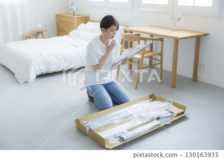 A woman assembling a clothes rack A woman assembling a clothes rack 130163935