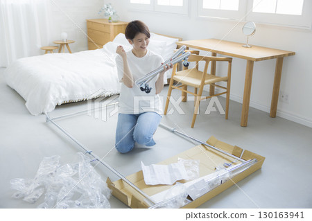 A woman assembling a clothes rack 130163941