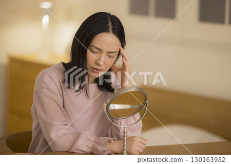 A woman doing skin care at night in her bedroom A woman doing skin care at night in her bedroom 130163982