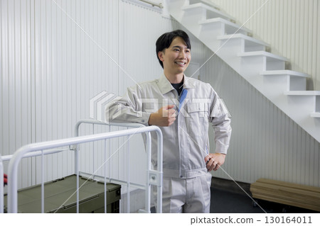 一名身穿工作服的男子在倉庫裡推著手推車 130164011