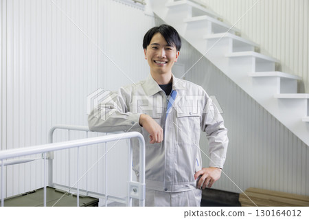 A man in work clothes pushing a cart in a warehouse 130164012