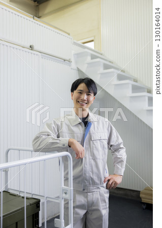 一名身穿工作服的男子在倉庫裡推著手推車 130164014