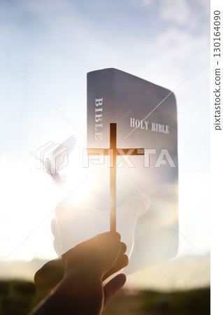 A holy bible, the cross of Jesus Christ, a dove, a brightly shining sun, and a sunset landscape background. A holy bible, the cross of Jesus Christ, a dove, a brightly shining sun, and a sunset landscape background. 130164090