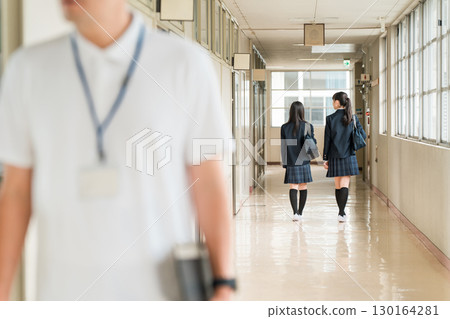 一名身穿制服的女學生和一名身穿 Polo 衫的男老師走在學校走廊上 一名身穿制服的女學生和一名身穿 Polo 衫的男老師走在學校走廊上 130164281
