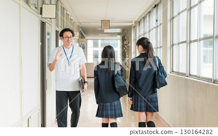 一名男老師和女學生在學校走廊互相打招呼 130164282