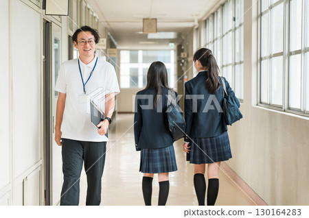 一名男老師和女學生在學校走廊互相打招呼 一名男老師和女學生在學校走廊互相打招呼 130164283