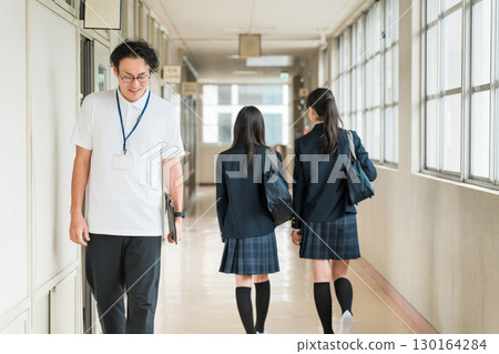一名男老師和女學生在學校走廊互相打招呼 一名男老師和女學生在學校走廊互相打招呼 130164284