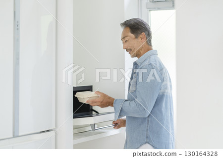 Senior man using a microwave 130164328