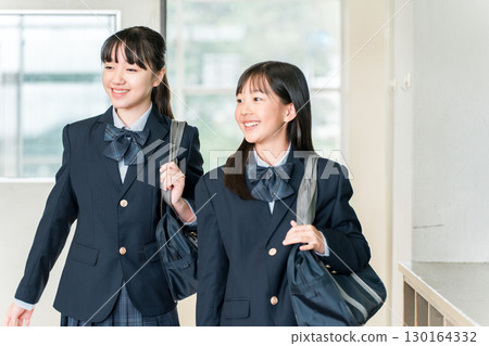 Elementary school, junior high school, and high school girls in uniforms entering the classroom smiling and chatting 130164332