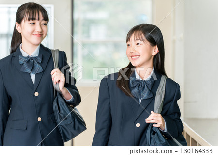 Elementary school, junior high school, and high school girls in uniforms entering the classroom smiling and chatting 130164333